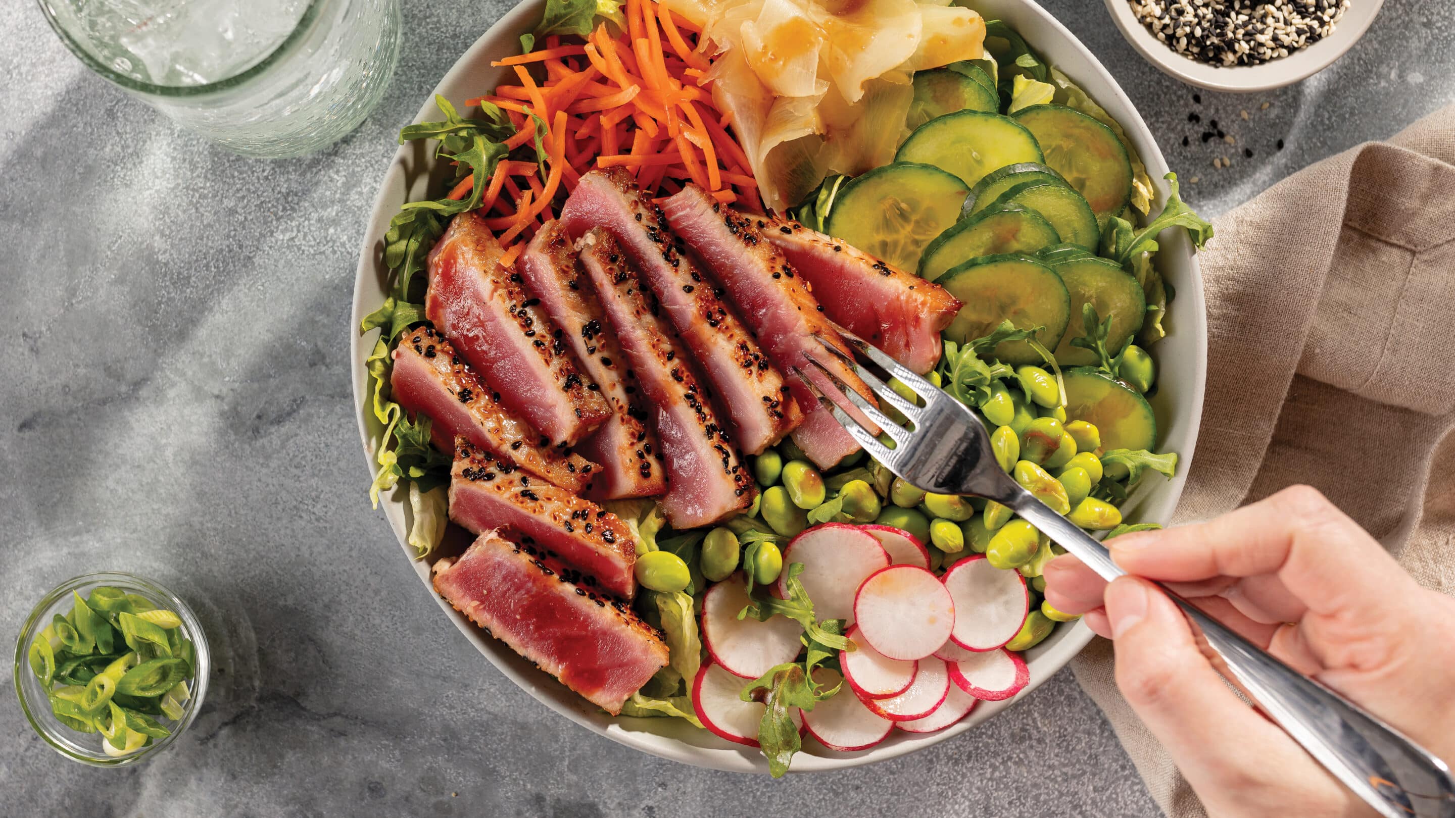 yellowfin tuna sushi salad bowl recipe Yellowfin tuna sushi salad bowl with greens, cartots, cucumbers, edamame, radishes and ginger with sliced medium-rare tuna.