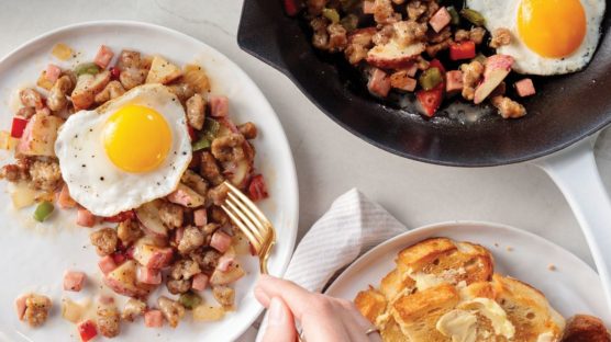 skillet breakfast with sunny side up egg on white plate. skillet and toast with butter in background