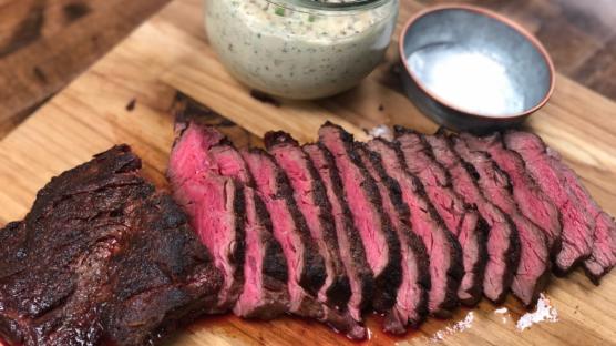 Ribeye Cap Roast sliced on cutting board with smoky bacon, chive and shallot butter in serving dish