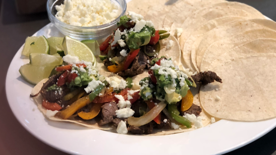 flat iron steak fajita with tomato and avocado salsa and queso fresca cheese on a flour tortilla