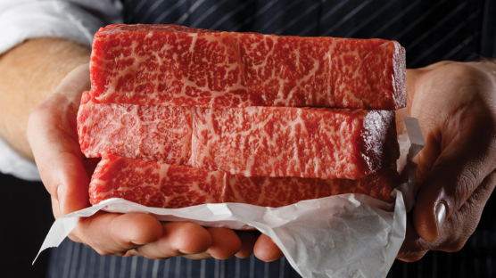 3 wagyu new york strips steak on butcher's paper held with two hands