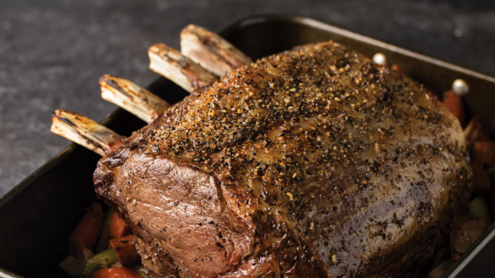 prime rib roast in roasting rack with rosemary & thyme au jus