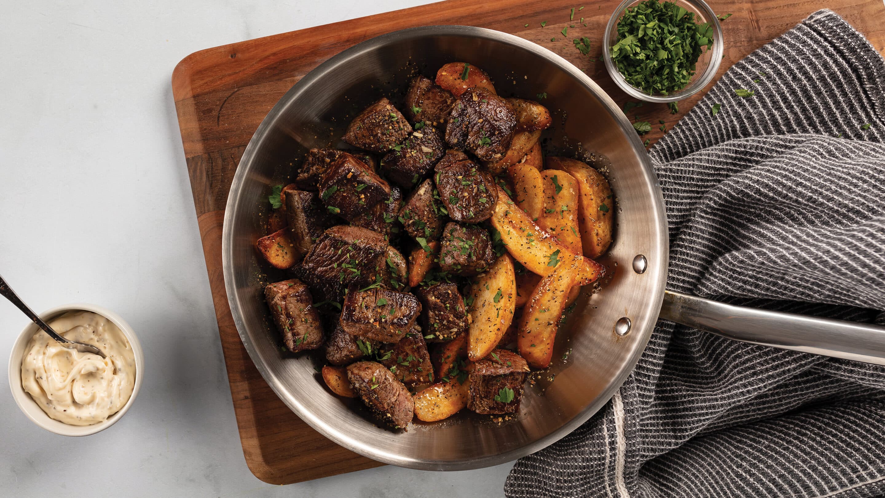 skillet with steak tips and fries.