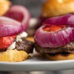 Garlic herb cheeseburgers with grilled onions and peppers on platter