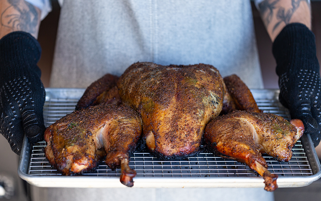 Man holding spatchcocked and smoked turkey