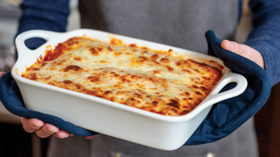 Woman holding tray of cooked lasagna