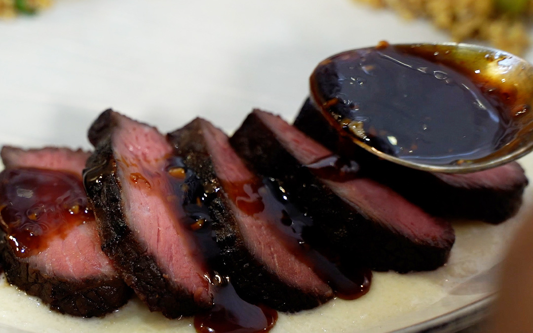 Pouring sweet soy sauce over sliced top sirloin