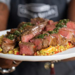 Perfectly cooked and sliced medium-rare porterhouse steak seasoned with African spices and cooking using the reverse sear method. Served on a bed of curried shrimp pearl pasta and drizzled with collard green chimichurri.