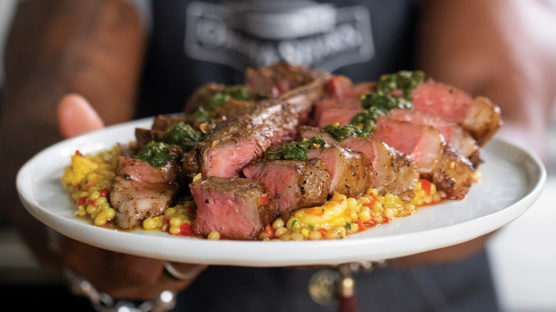 Perfectly cooked and sliced medium-rare porterhouse steak seasoned with African spices and cooking using the reverse sear method. Served on a bed of curried shrimp pearl pasta and drizzled with collard green chimichurri.