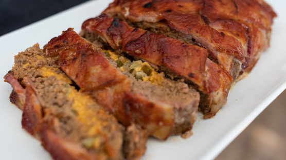 Meatloaf stuffed with cheese and pickles and topped with bacon