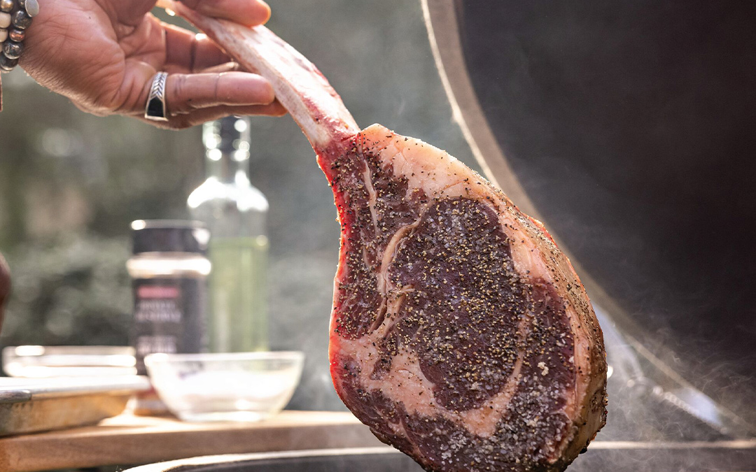 Setting a well-marbled tomahawk ribeye on the smoker