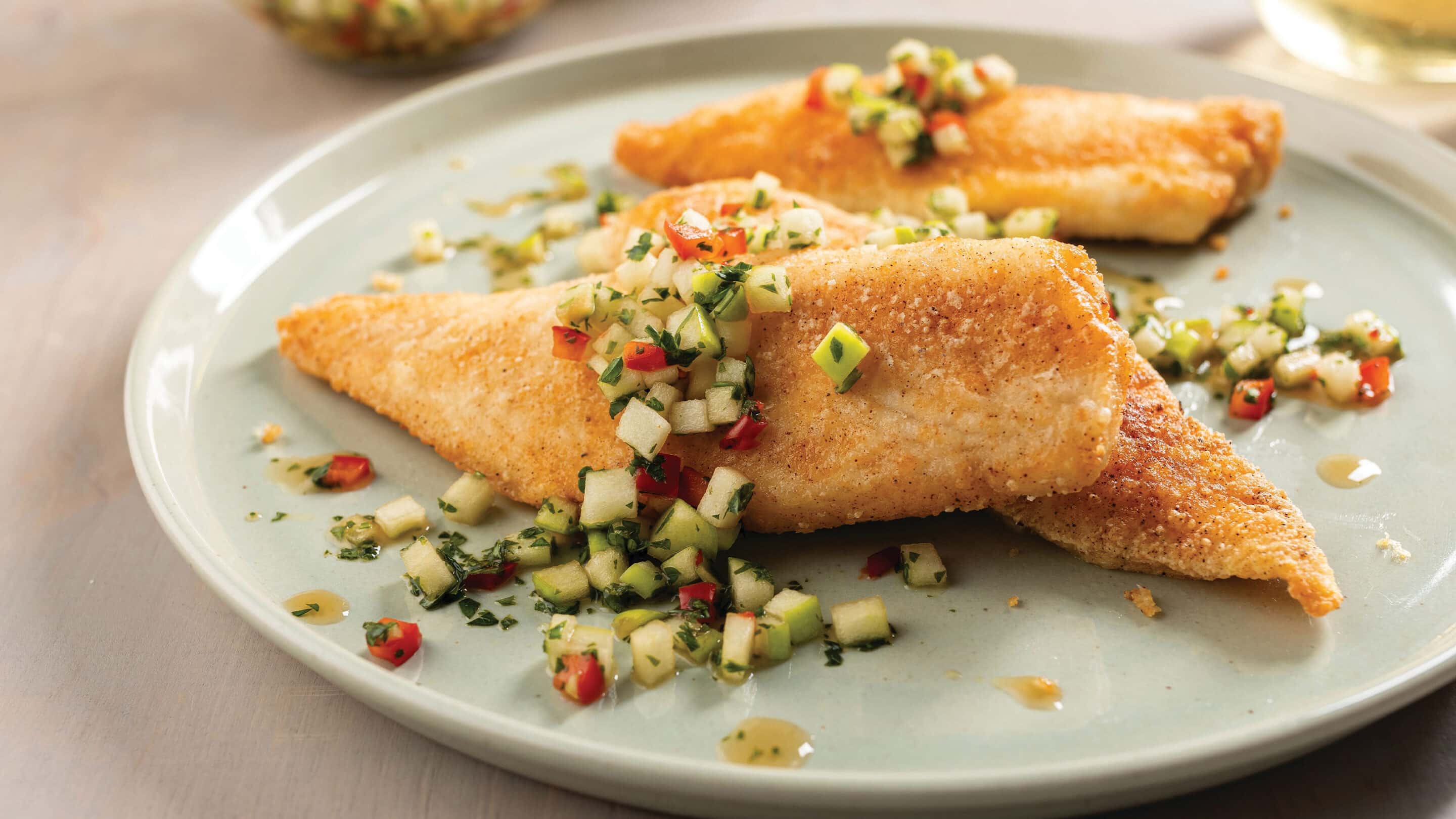 Tilapia with green apple chili sambal recipe Plate with 3 pan-seared tilapia fillets topped with green apple chili sambal.